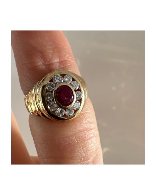 טבעת זהב צהוב 14 קראט בסגנון חותם עגול, משובצת אבן רובי מרכזית וסביבה הילה של יהלומים עגולים.