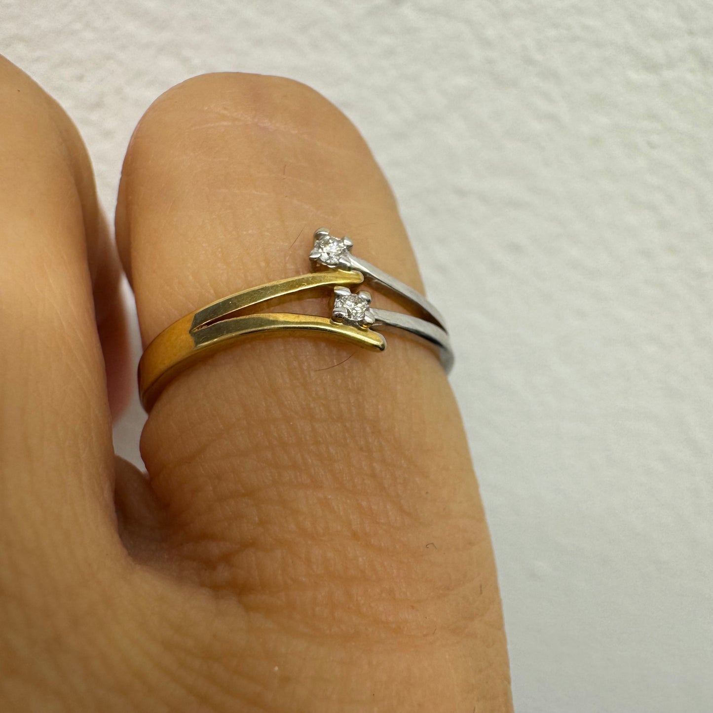 טבעת זהב 14 קראט, עם זרועות מצטלבות בזהב צהוב וזהב לבן, שכל אחת מהן משובצת יהלום קטן ונוצץ.