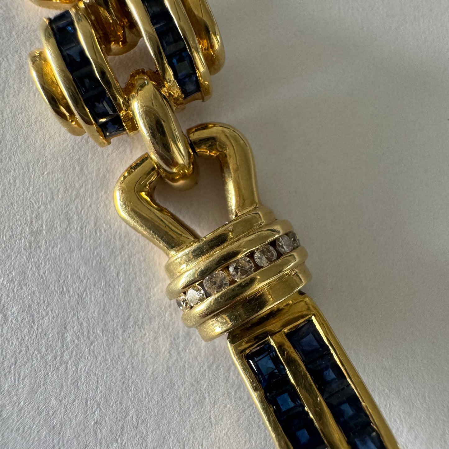 18K gold bracelet featuring a bold link design set with deep blue Sapphires and a subtle Diamond accent at the center.
