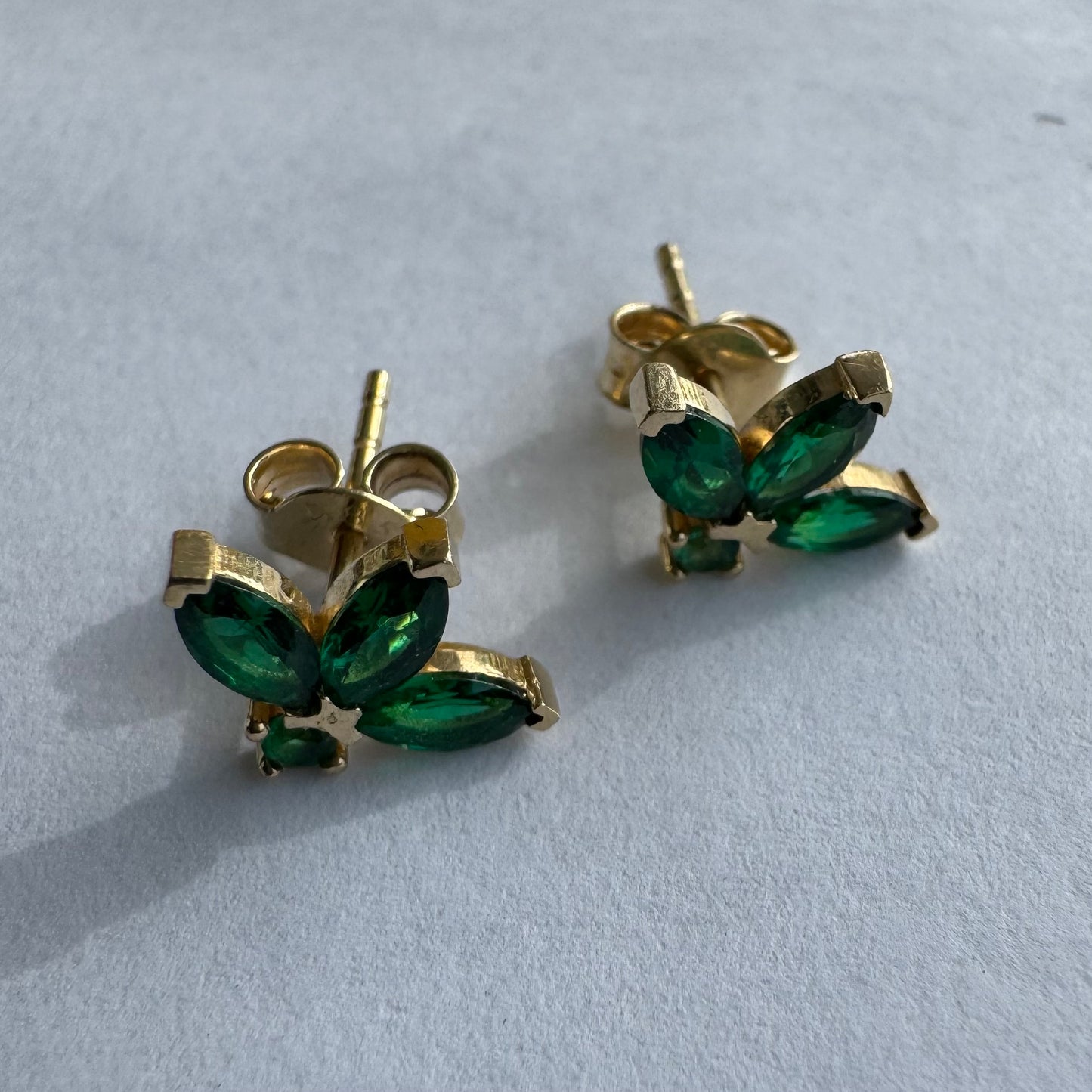 עגילים צמודיפ לאוזן מזהב 14 קראט, בעיצוב פרח עדין משובצים אבני אמרלד בחיתוך מרקיזה היוצר מראה אלגנטי, נקי ועל-זמני.