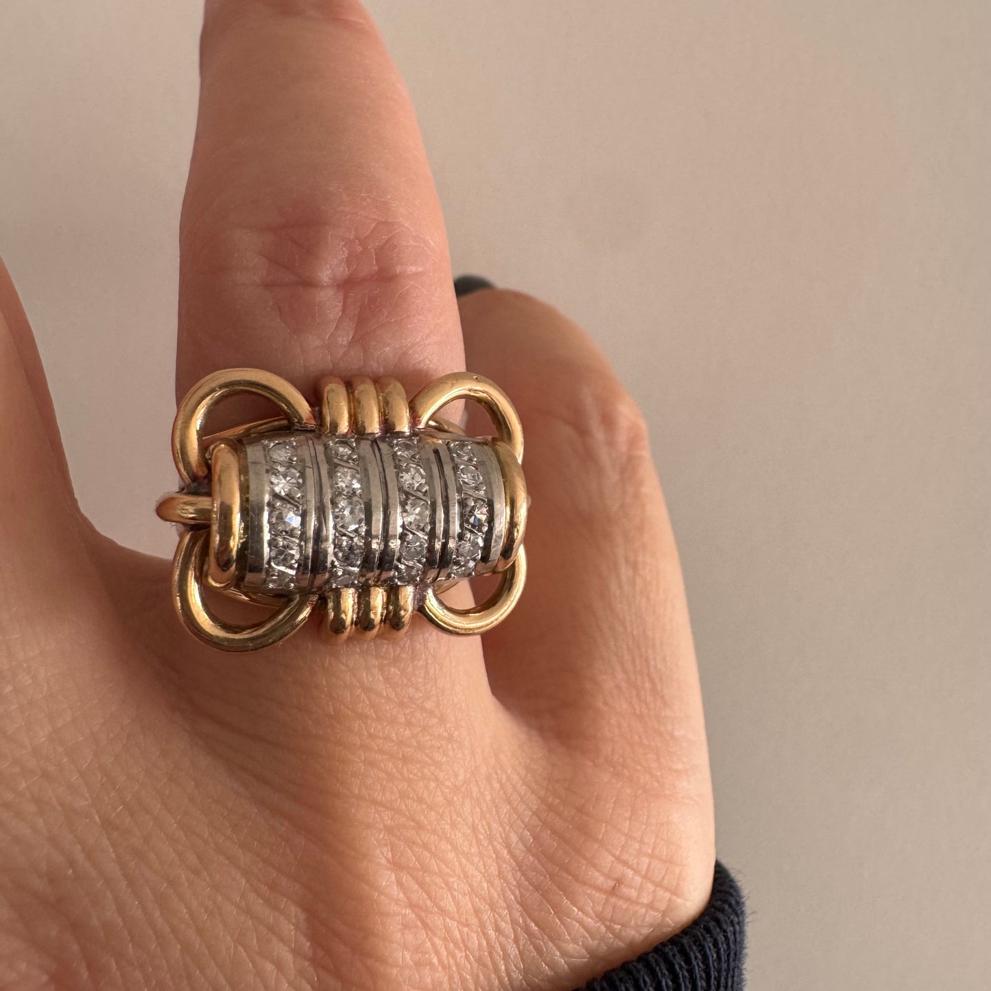 טבעת זהב צהוב ולבן 18 קראט עם מרכז בצורת חבית, משובצת יהלומים נוצצים.