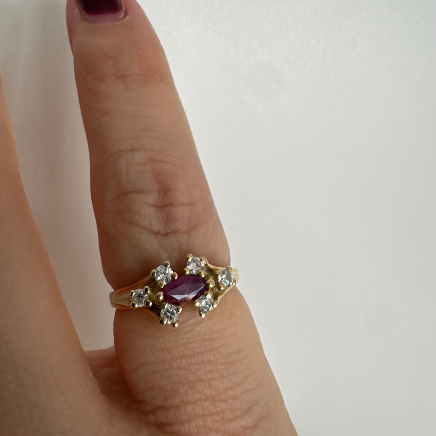 18K gold ring set with a marquise-cut Ruby accented by round Diamonds on each side.