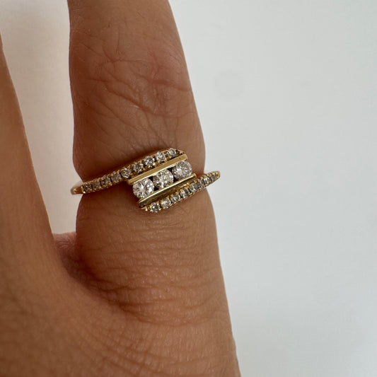 טבעת זהב צהוב 14 קראט בעיצוב ייחודי, משובצת שלושה יהלומים מרכזיים ושורות נוספות של יהלומים לאורך הזרועות. 