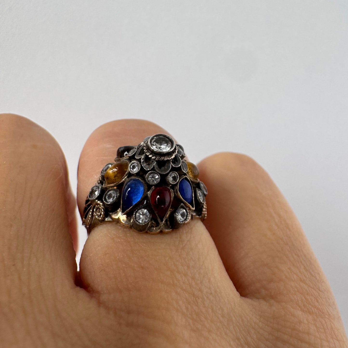 14K gold ring set with a central transparent gemstone surrounded by a vibrant mosaic of colorful gemstones -set in an ornate, handcrafted design