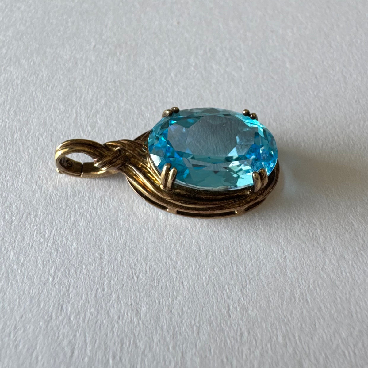 9K gold Pendant set with a striking oval-cut Blue Topaz