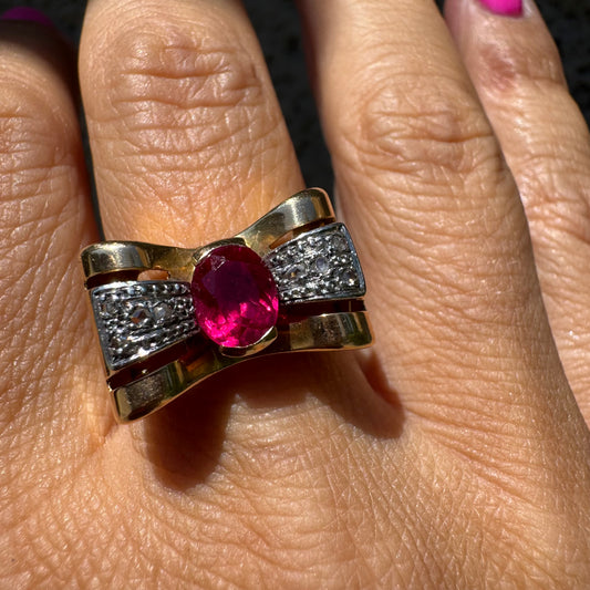 18K gold ring in a sculptural bow-inspired design.
Set with a vivid oval-cut Ruby at the center, framed by shimmering Diamonds