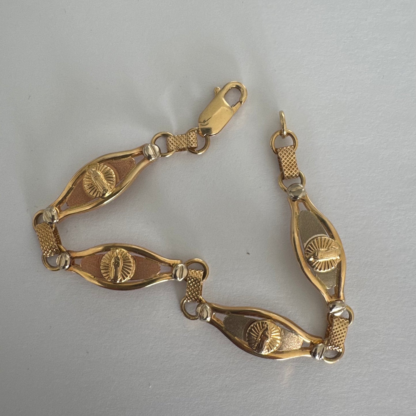 צמיד זהב צהוב 14 קראט עם אלמנט מרכזי בדמות מריה הקדושה, מוקפת קרני אור.