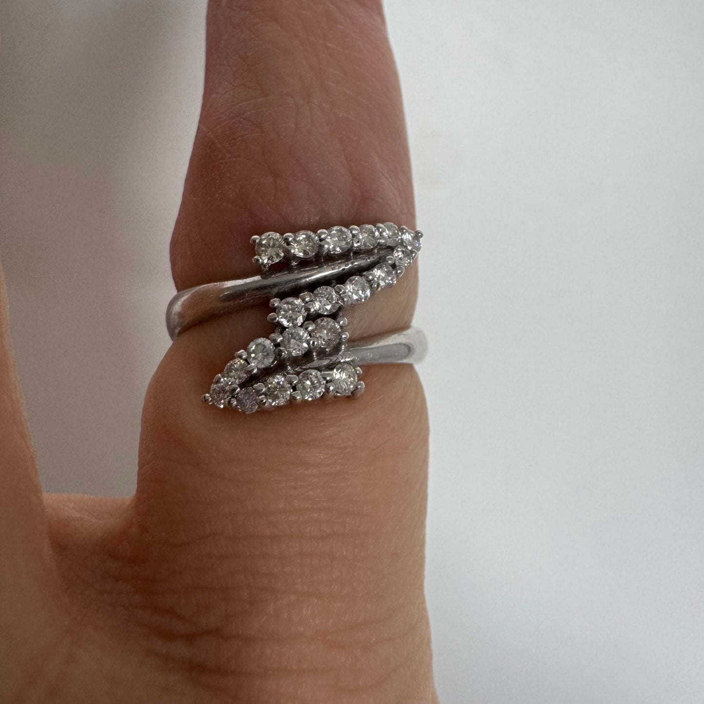 14K gold ring with an open design, featuring two curved rows of sparkling Diamonds that cross over each other elegantly.