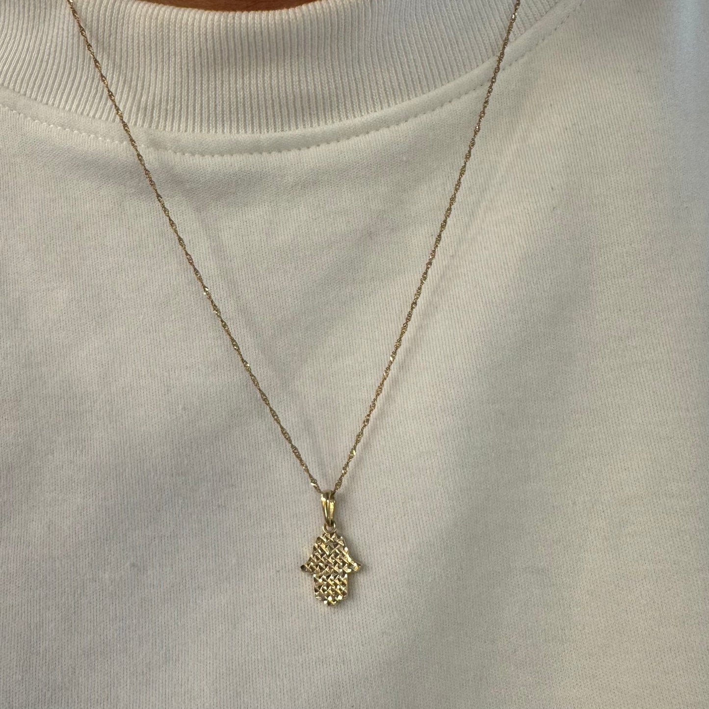 14K gold Hamsa pendant featuring a richly textured, light-catching finish.