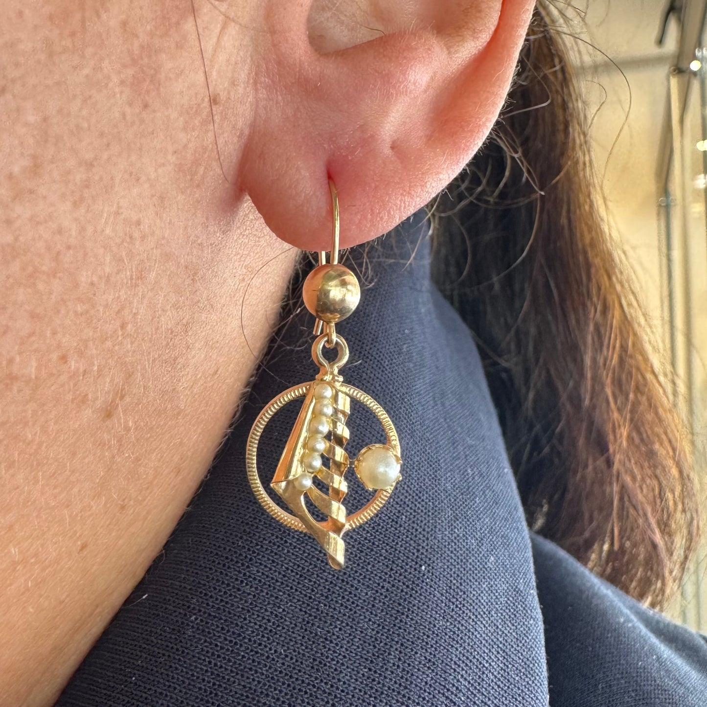 עגילי זהב 10 קראט, בעיצוב עדין עם אלמנט ספירלי ושילוב פנינים קטנות בגוון לבן-קרם. 