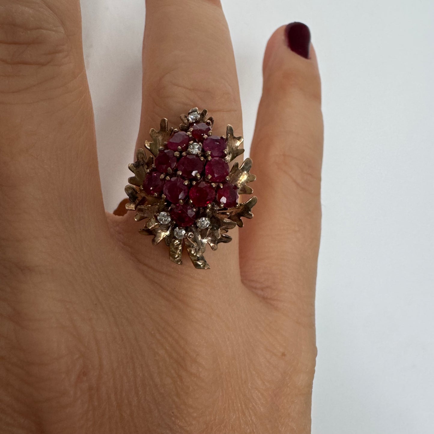 14K gold ring set with a vibrant cluster of deep red rubies and sparkling diamonds.