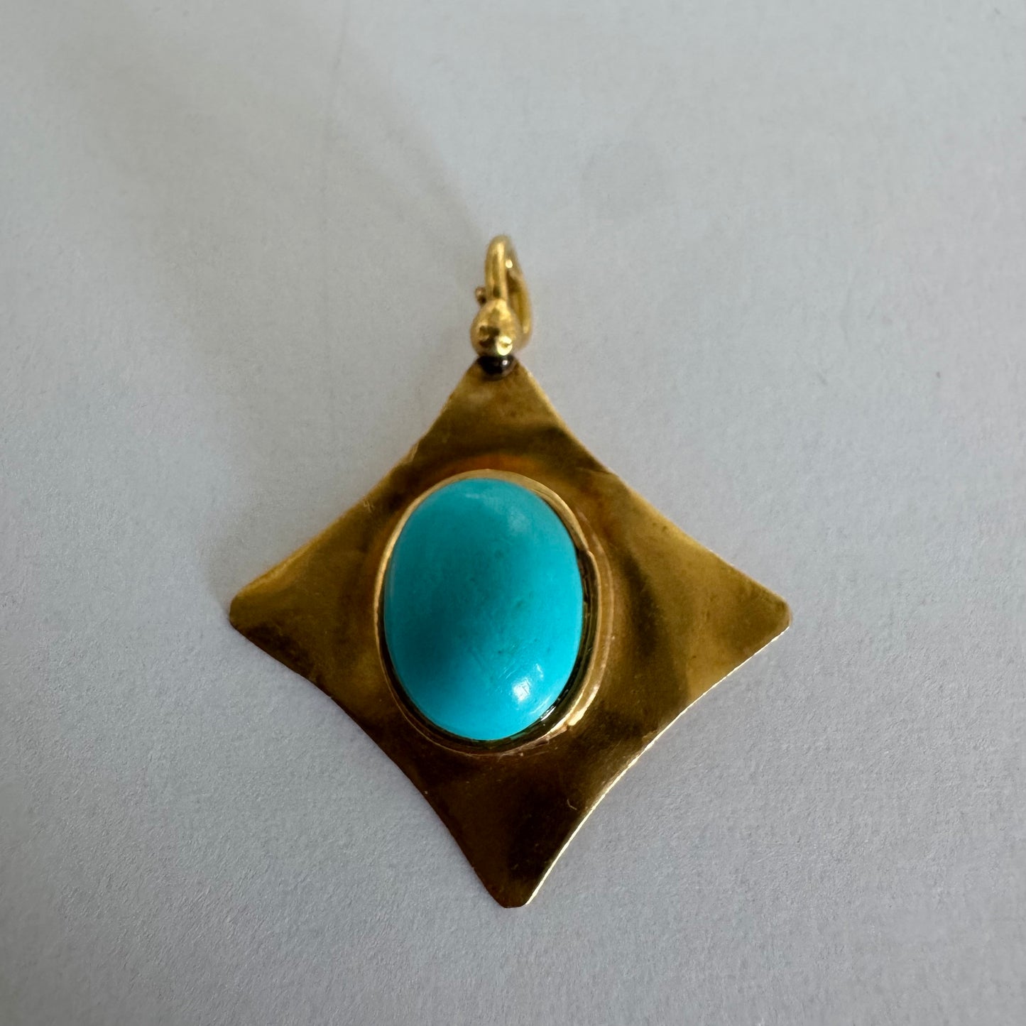 18K gold pendant set with a vibrant Turquoise stone in a bold, geometric design.