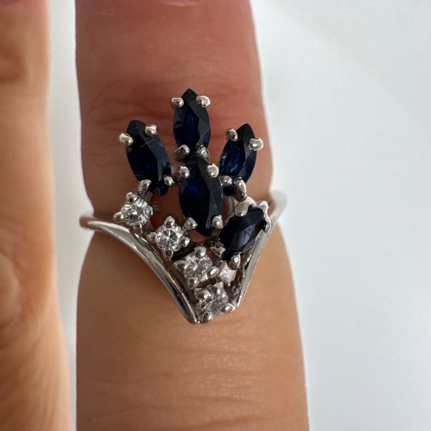 טבעת זהב לבן 14 קראט משובצת אבני ספיר כחולות בחיתוך מרקיזה ויהלומים, היוצרים מראה אלגנטי ודינמי.