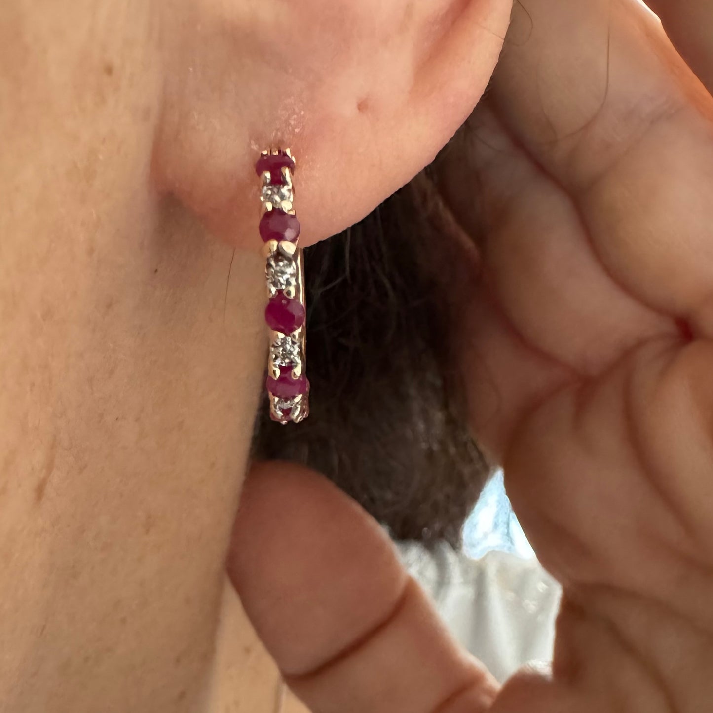 עגילי חישוק זהב צהוב 14 קראט משובצים אבני רובי בגוון אדום עמוק, בשילוב יהלומים המעניקים ברק עדין בין האבנים.