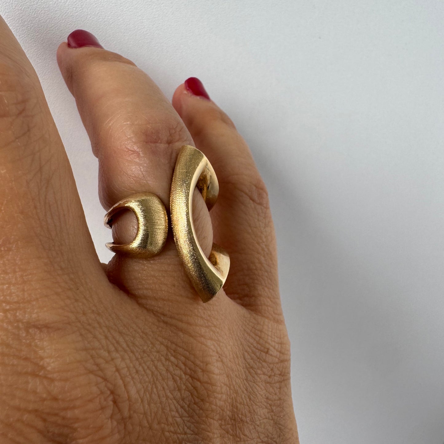 14K gold sculptural ring with a bold, modern design featuring flowing, asymmetrical lines.