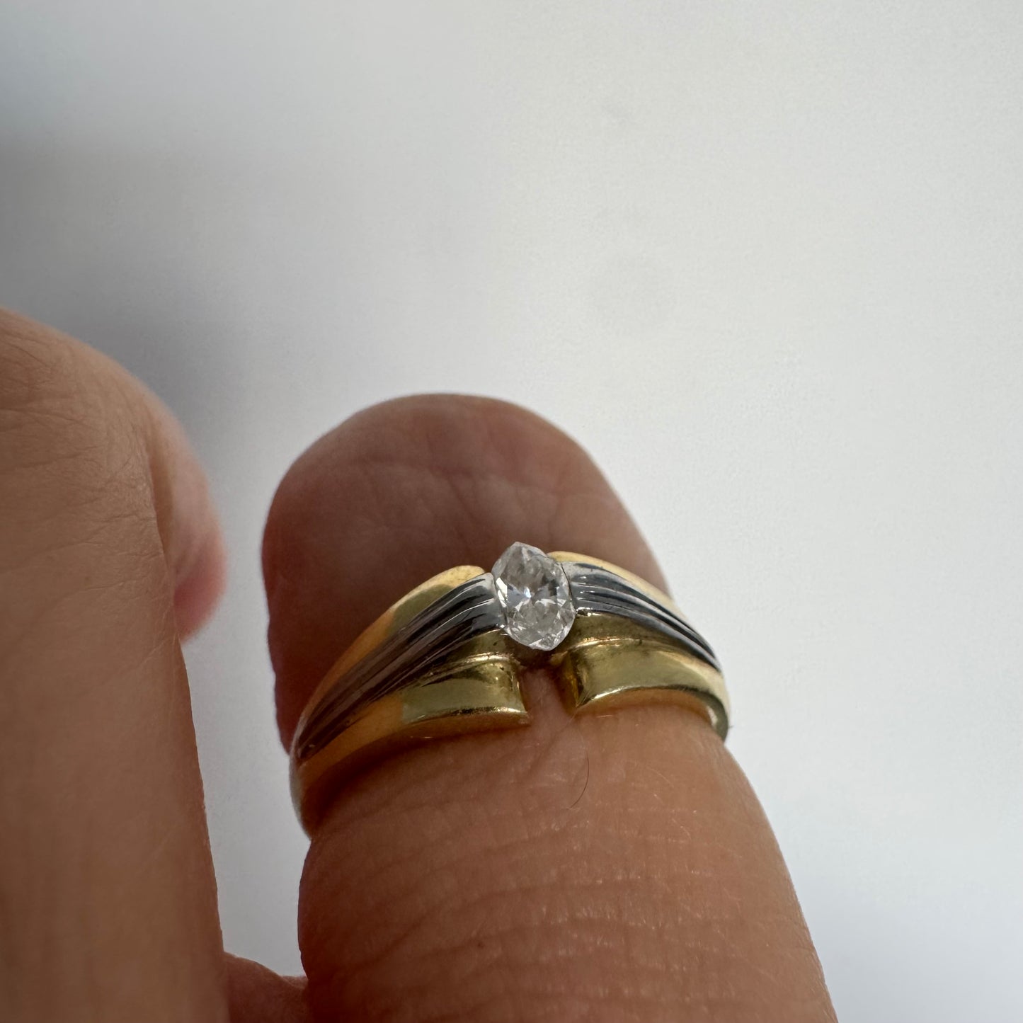 טבעת זהב 18 קראט בעיצוב דו-גוני של זהב צהוב ולבן, משובצת יהלום בחיתוך מרקיזה. 
