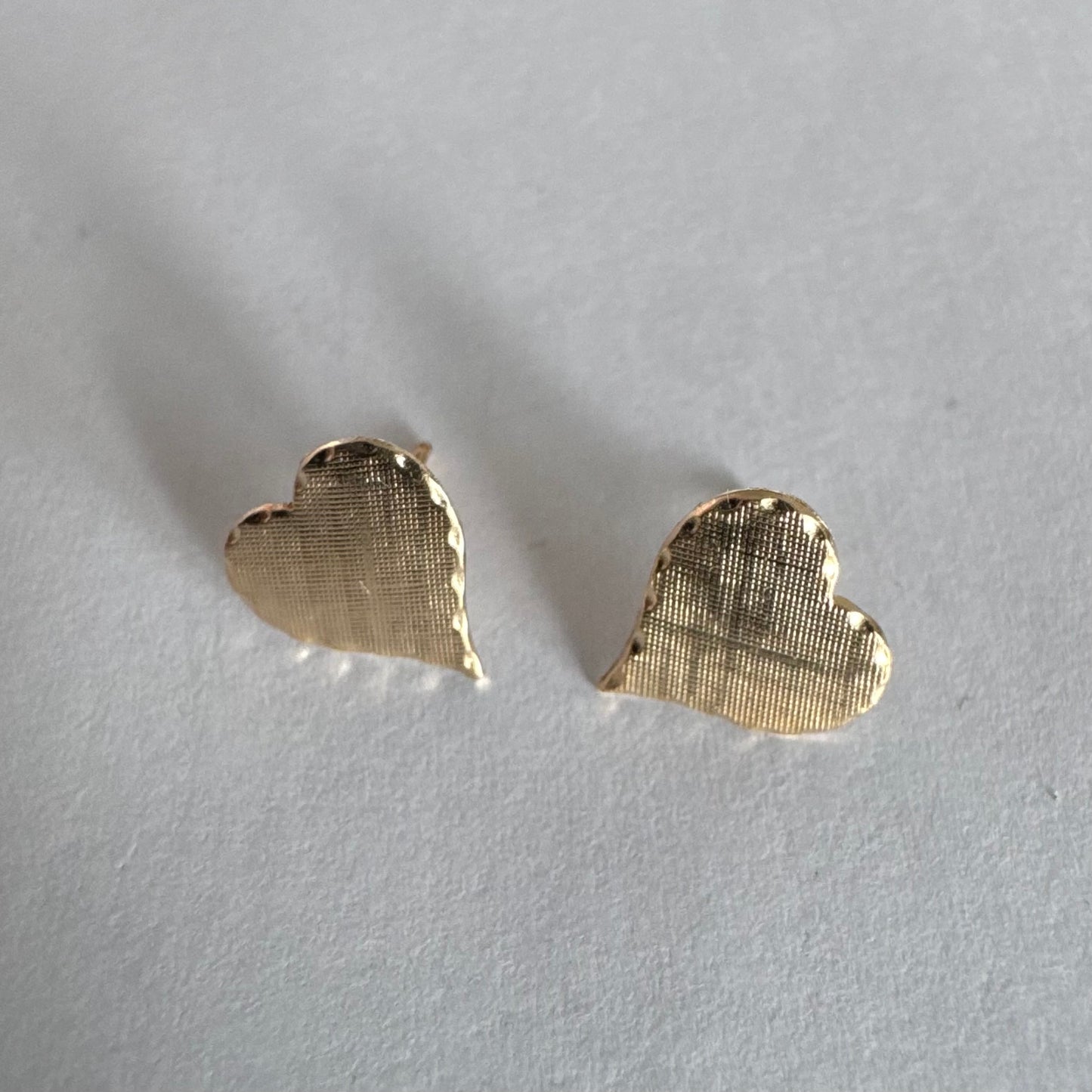 עגילי זהב צהוב 10 קראט בצורת לב, עם טקסטורה עדינה וגימור רך.