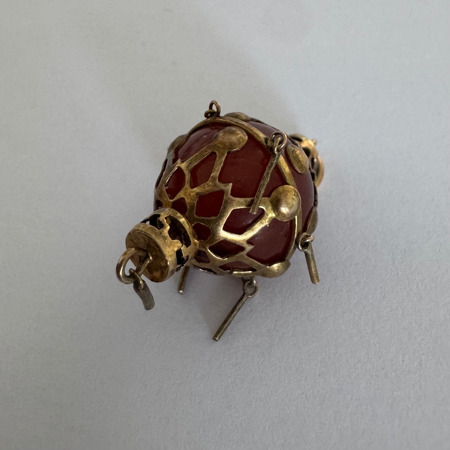 9K gold pendant set with a deep red stone in an intricate openwork design.
