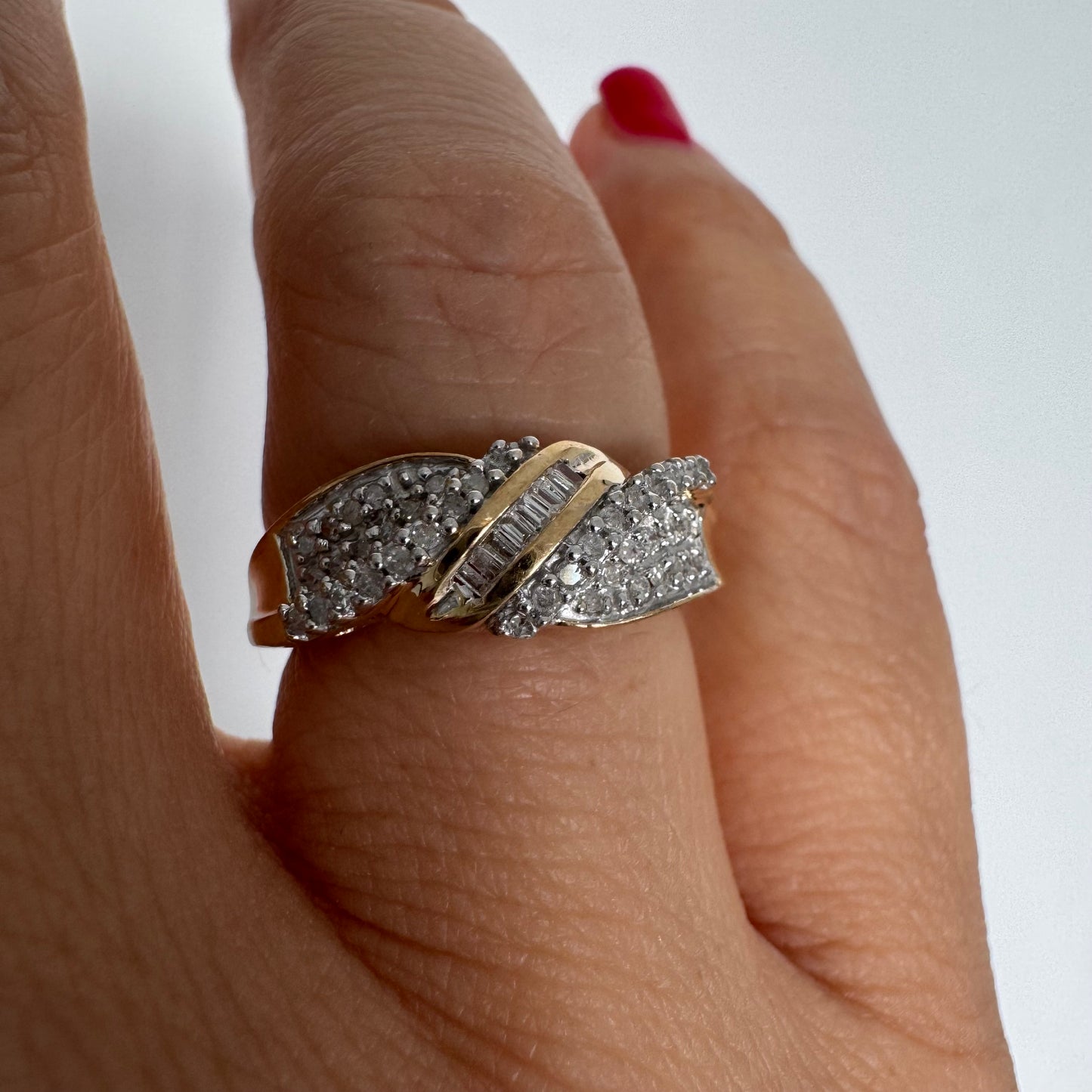 טבעת זהב 10 קראט משובצת יהלומים בחיתוך עגול לצד שורת יהלומי בגט במרכז.