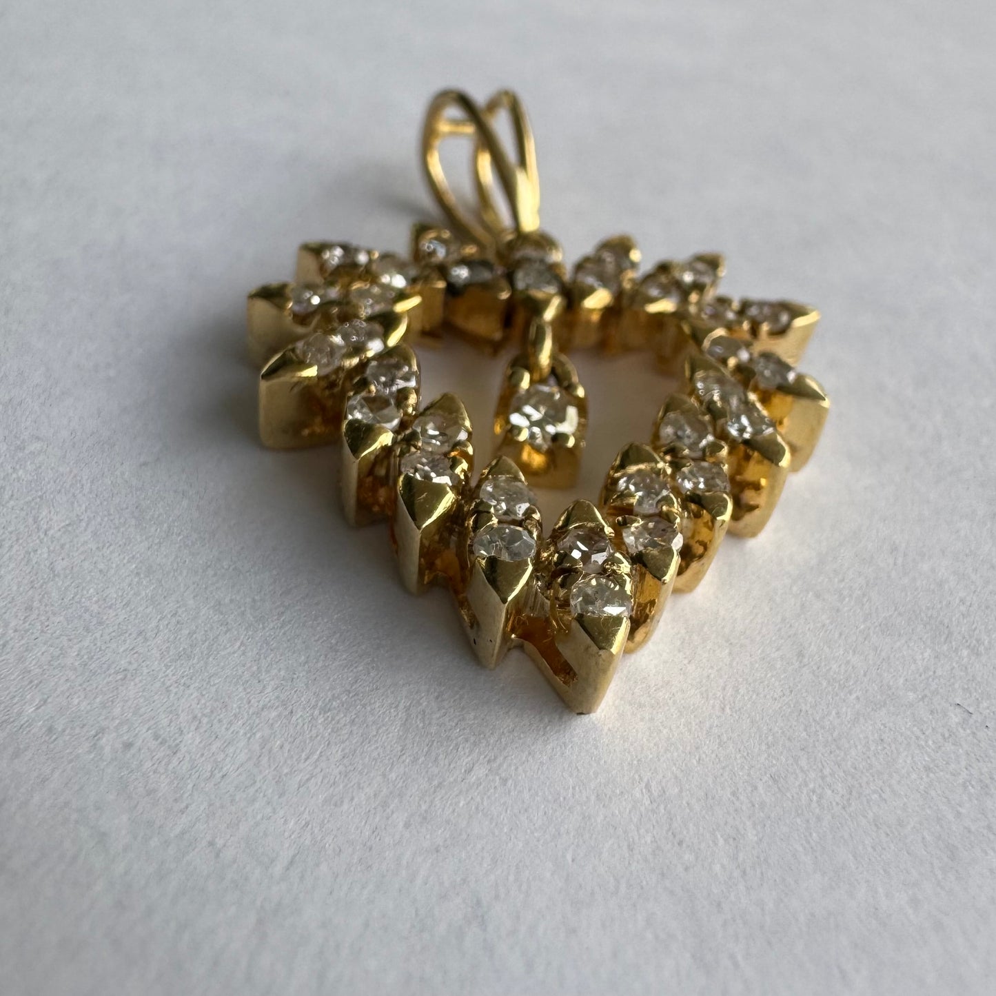 תליון זהב צהוב 14 קראט בצורת לב, משובץ יהלומים בסידור עדין היוצר מראה עשיר ומלא ברק.