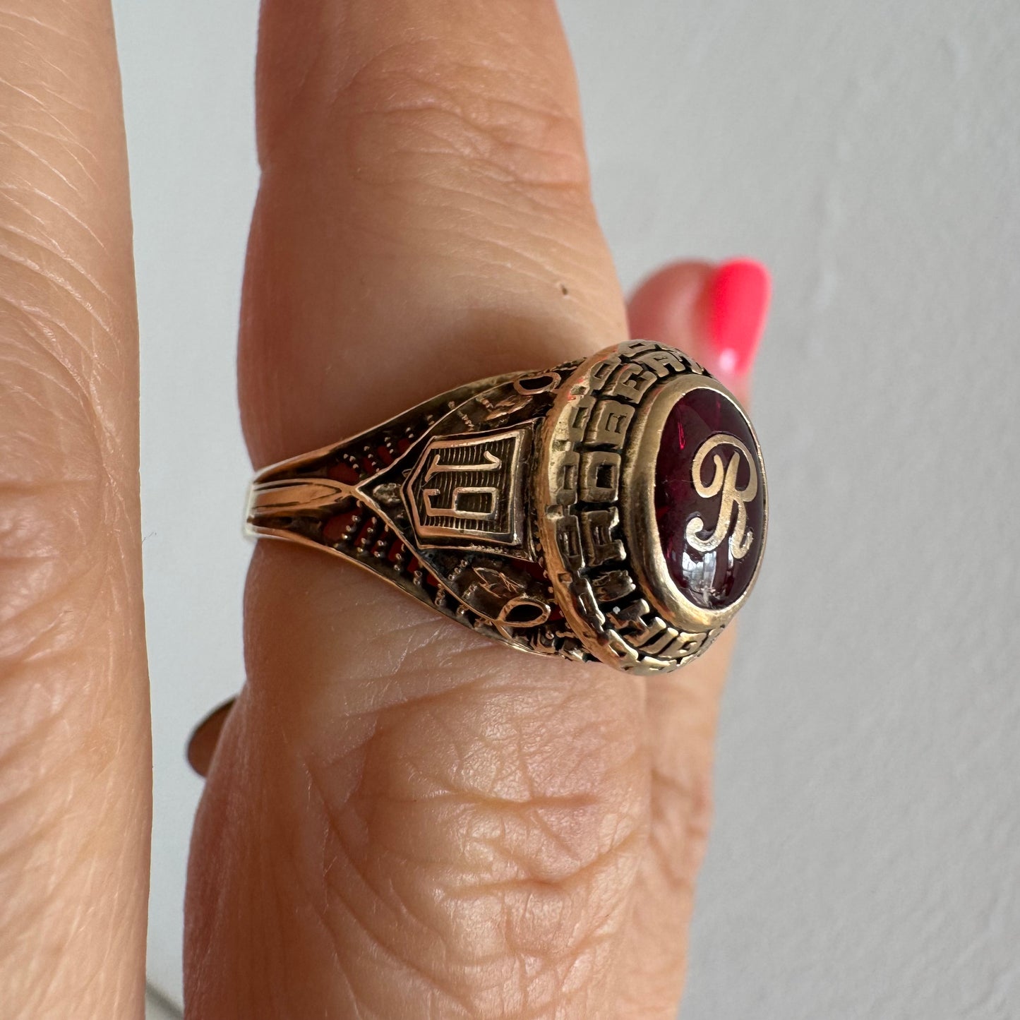 10K gold class ring featuring a rich red center stone engraved with the letter “R”.
