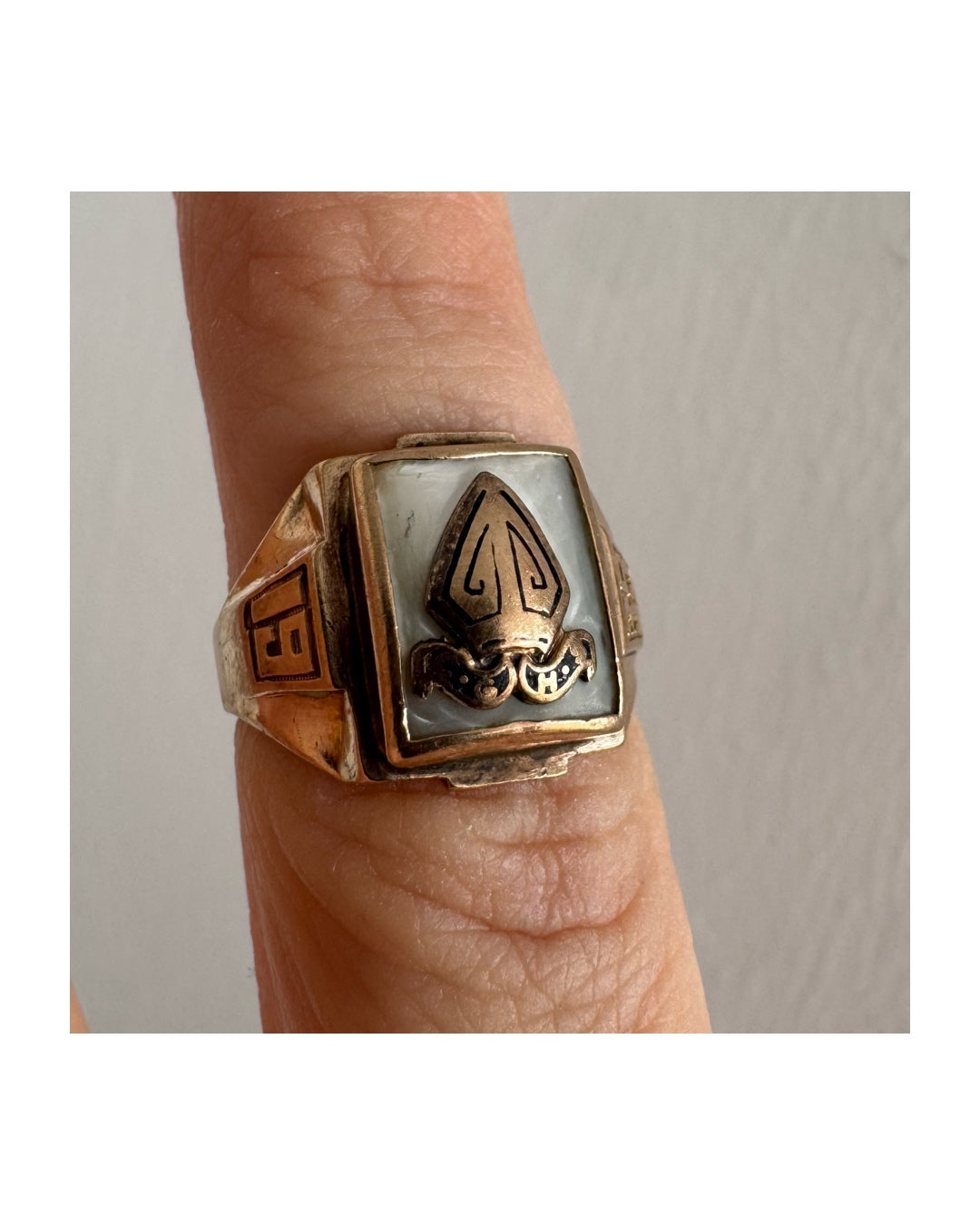 טבעת זהב 10 קראט בעיצוב חותם קלאסי, עם פלטה מרובעת משובצת לוח אם-הפנינה ועליה סמל פלר-דה-ליס מובלט.