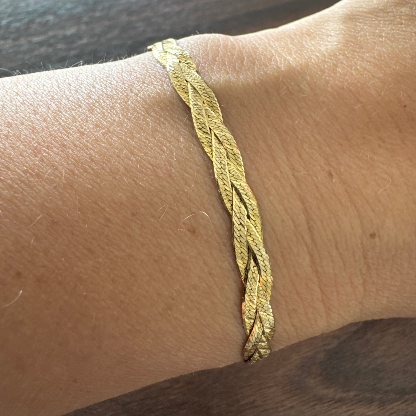 צמיד זהב צהוב 10 קראט בעיצוב קלוע עם טקסטורה עדינה שמחזירה אור וברק רך.