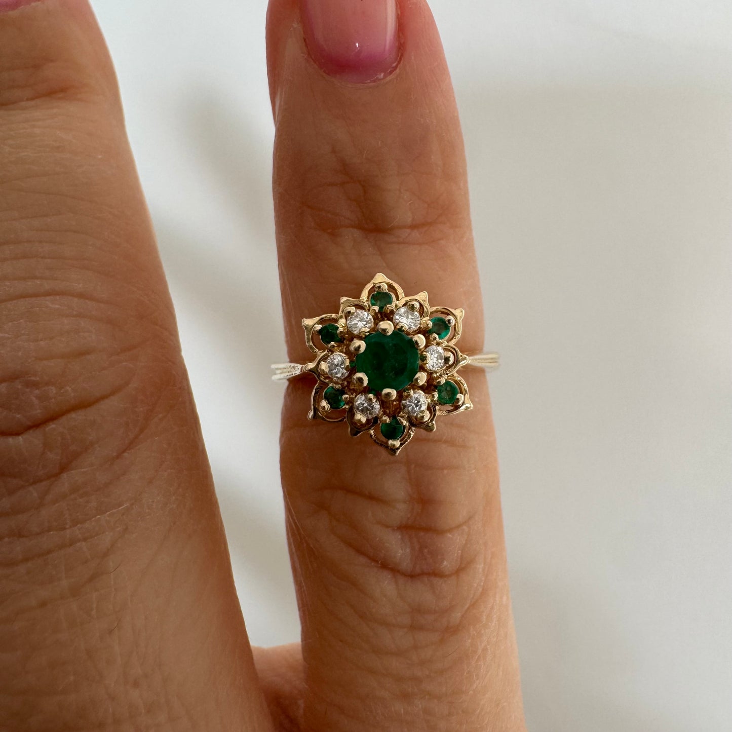 טבעת זהב 14 קראט בעיצוב פרח משובצת אבן אמרלד מרכזית, מוקפת יהלומים ואבני אמרלד נוספות