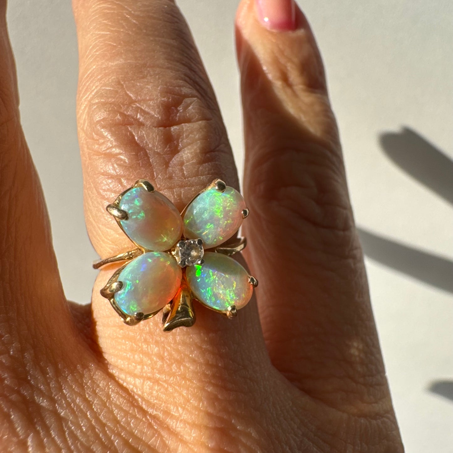 טבעת זהב 14 קראט בעיצוב פרח, משובצת ארבע אבני אופל בחיתוך טיפה ובמרכז יהלום טבעי.