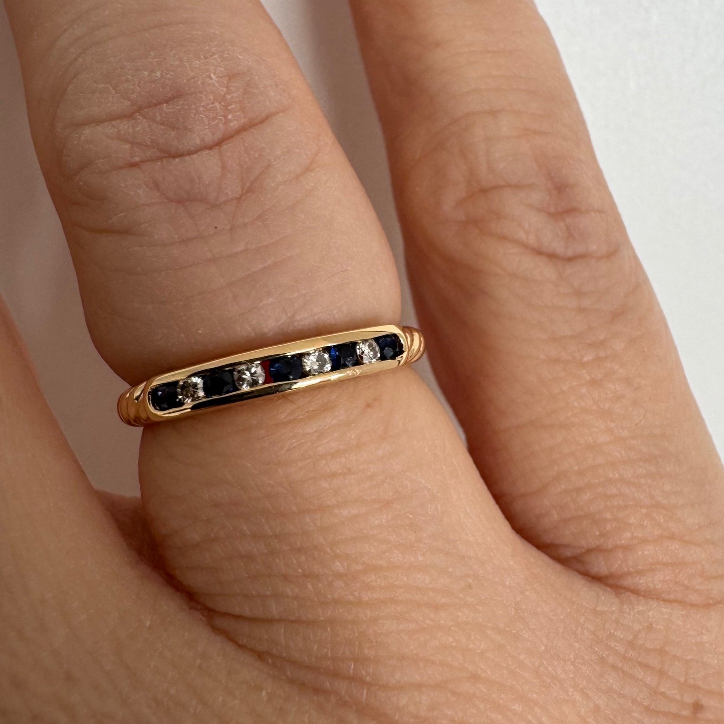 18K gold ring featuring a refined channel setting of deep blue Sapphires accented with Diamonds.