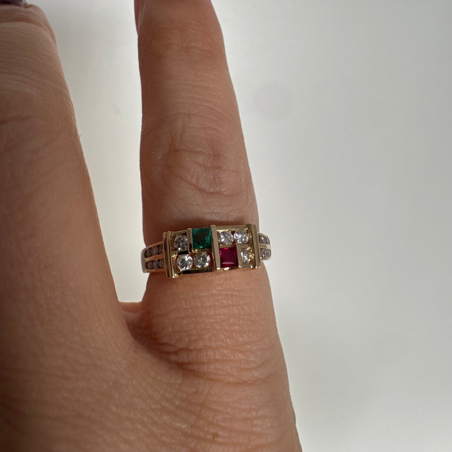 טבעת זהב צהוב 18 קראט בעיצוב גאומטרי מדורג, משובצת יהלומים עגולים לצד אבני אמרלד ורובי בחיתוך מלבני.