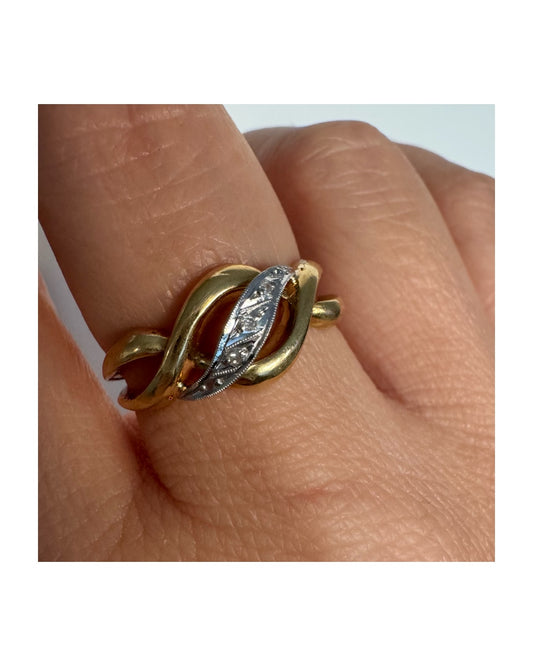 טבעת זהב צהוב 18 קראט בעיצוב קשר קלאסי, בשילוב אלמנט מרכזי מזהב לבן משובץ יהלומים עדינים.