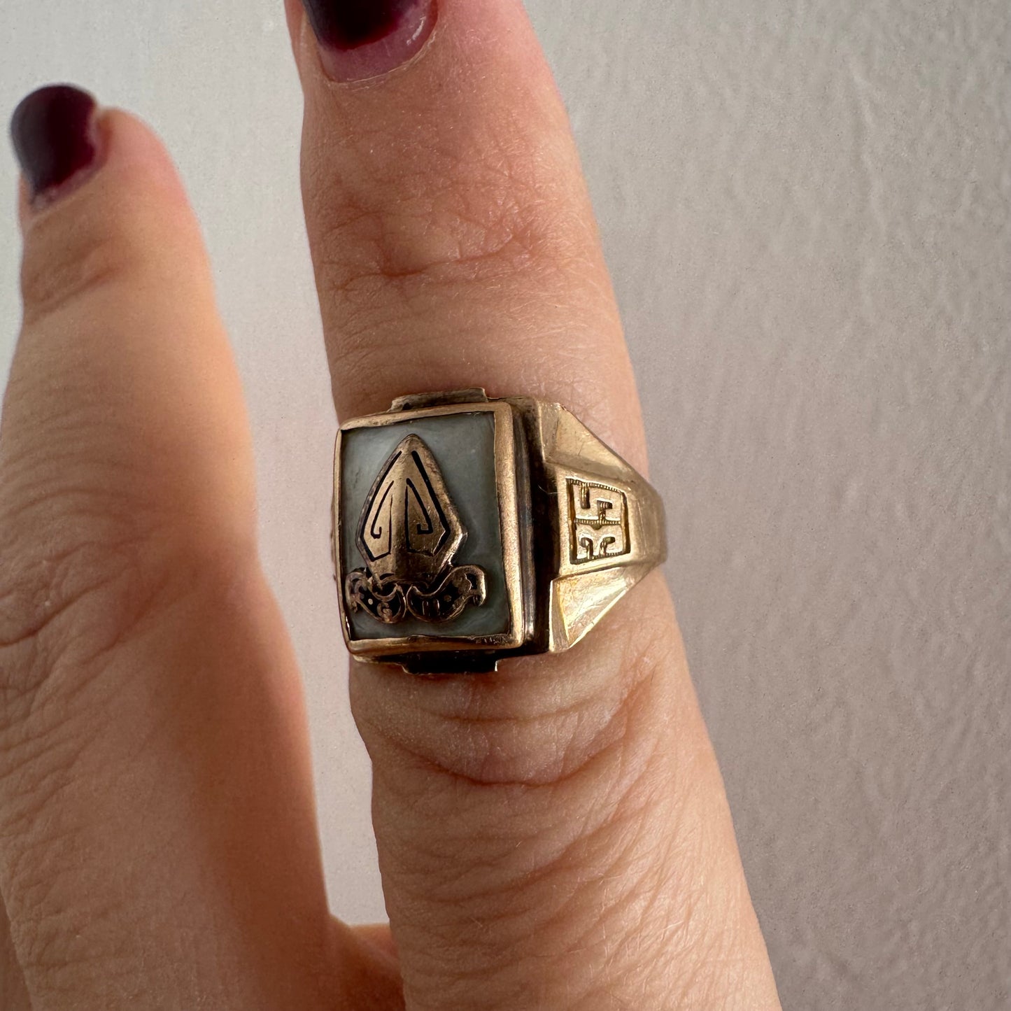 טבעת זהב 10 קראט בעיצוב חותם קלאסי, עם פלטה מרובעת משובצת לוח אם-הפנינה ועליה סמל פלר-דה-ליס מובלט.