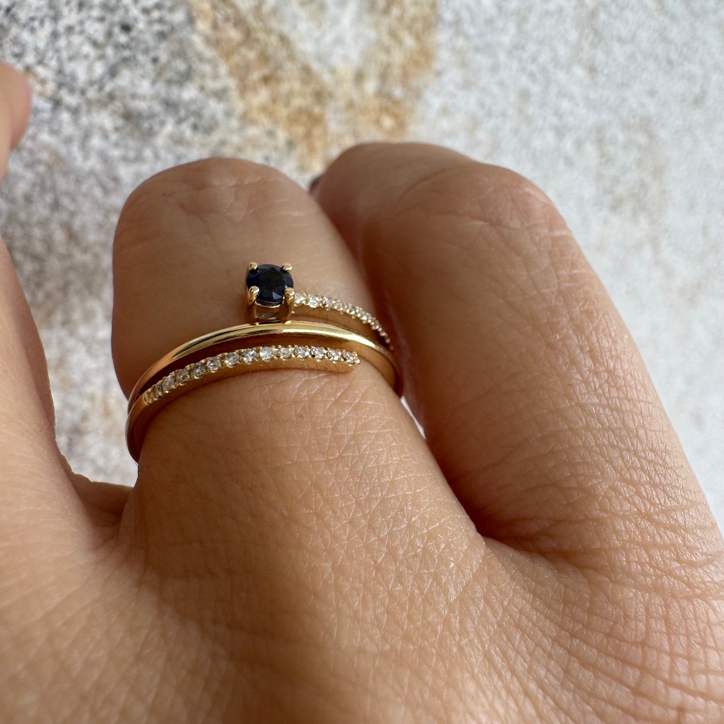 טבעת זהב צהוב 14 קראט משובצת אבן ספיר כחולה ויהלומים נוצצים בשורות עדינות.