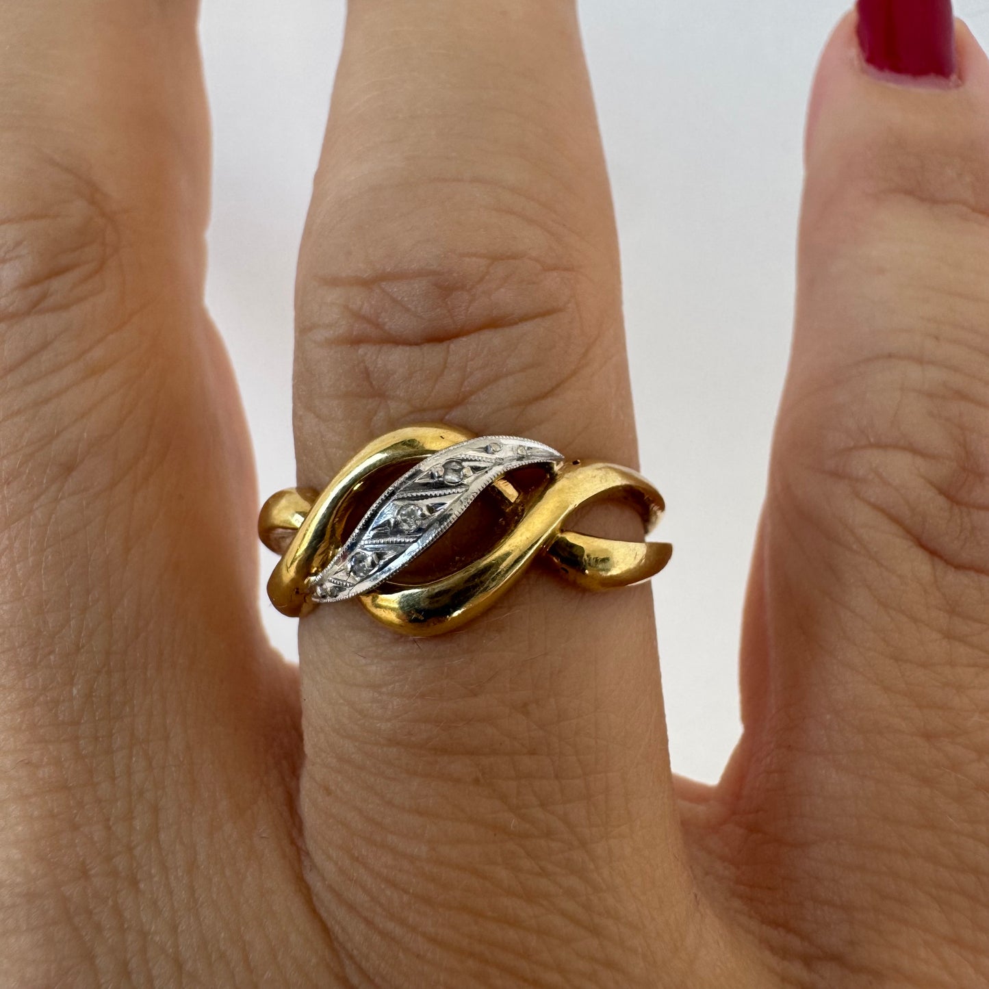 18K gold knot-style ring featuring a white gold center accented with delicate Diamonds.