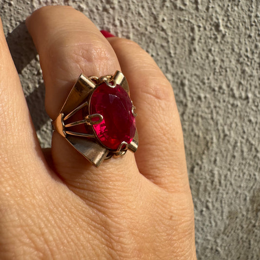 טבעת זהב 14 קראט משובצת אבן אובלית גדולה בצבע אדום חי במסגרת גאומטרית מיוחדת.