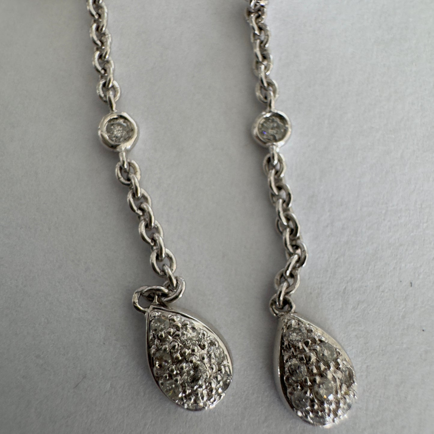 14K gold drop earrings featuring a delicate chain design with sparkling teardrop pendants.