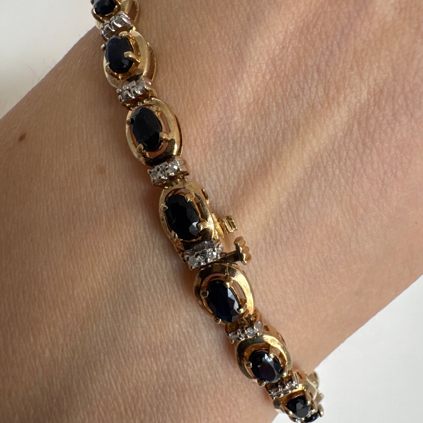 צמיד זהב צהוב 10 קראט בעיצוב קלאסי ועשיר, משובץ אבני ספיר אובליות בגוון כחול עמוק וביניהן שיבוצי יהלומים לבנים עדינים.