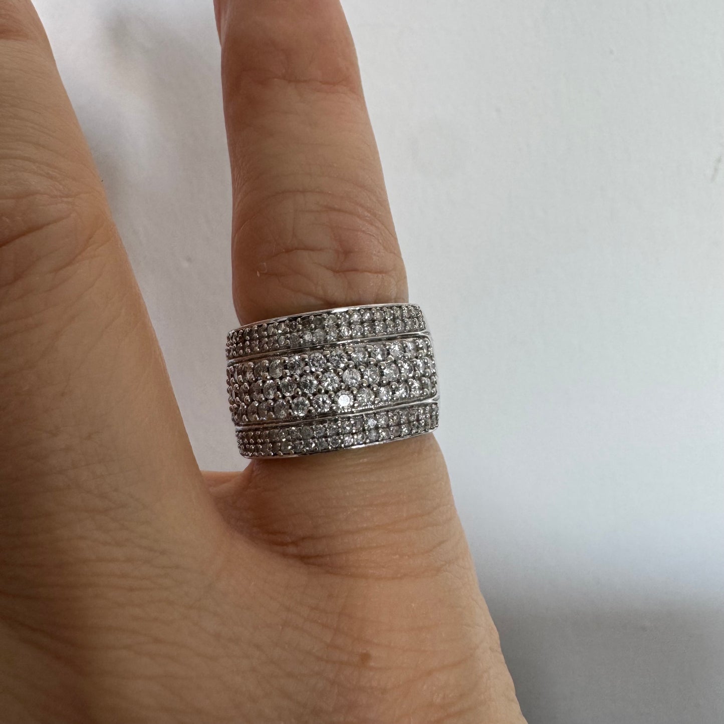 טבעת זהב לבן 18 קראט בעיצוב רחב ומרשים, משובצת יהלומים בשיבוץ פאווה צפוף המעניק ברק עשיר ונוכחות יוקרתית מכל זווית.