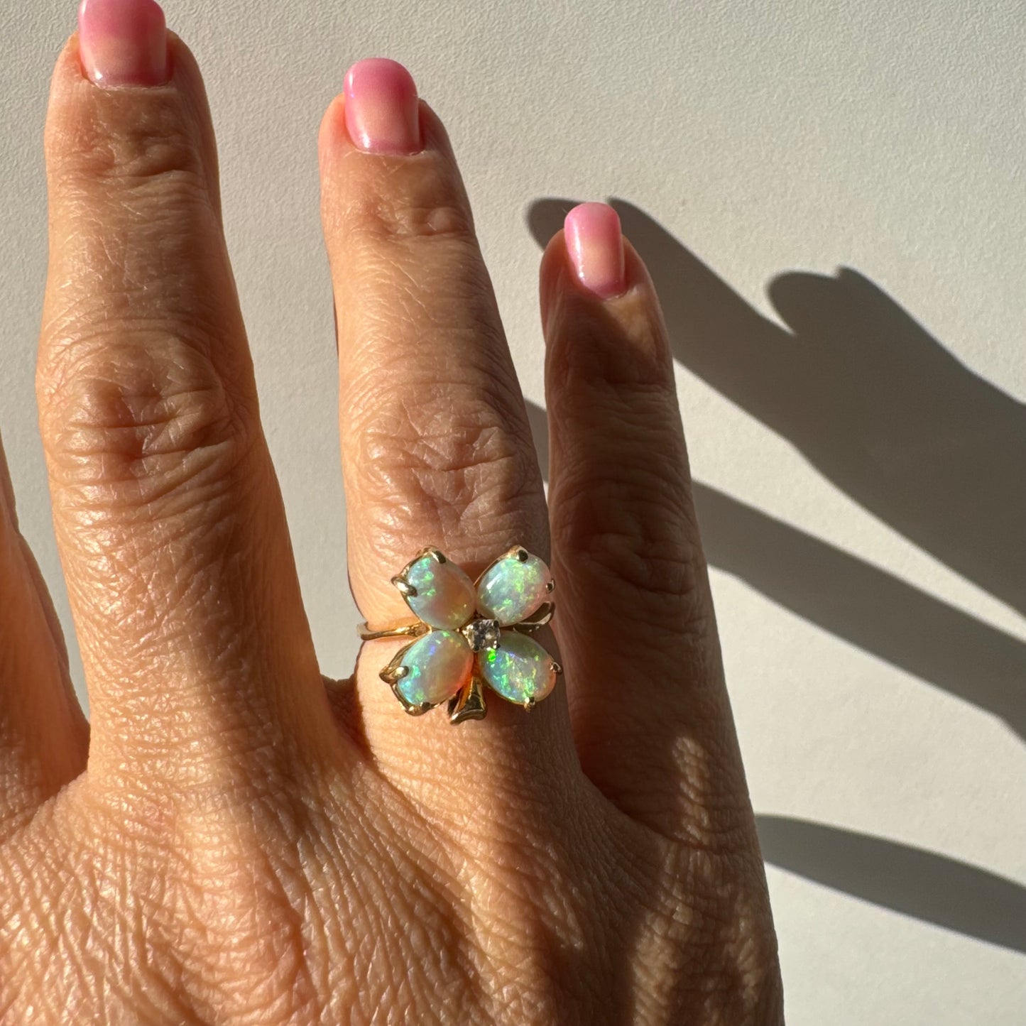 טבעת זהב 14 קראט בעיצוב פרח, משובצת ארבע אבני אופל בחיתוך טיפה ובמרכז יהלום טבעי.