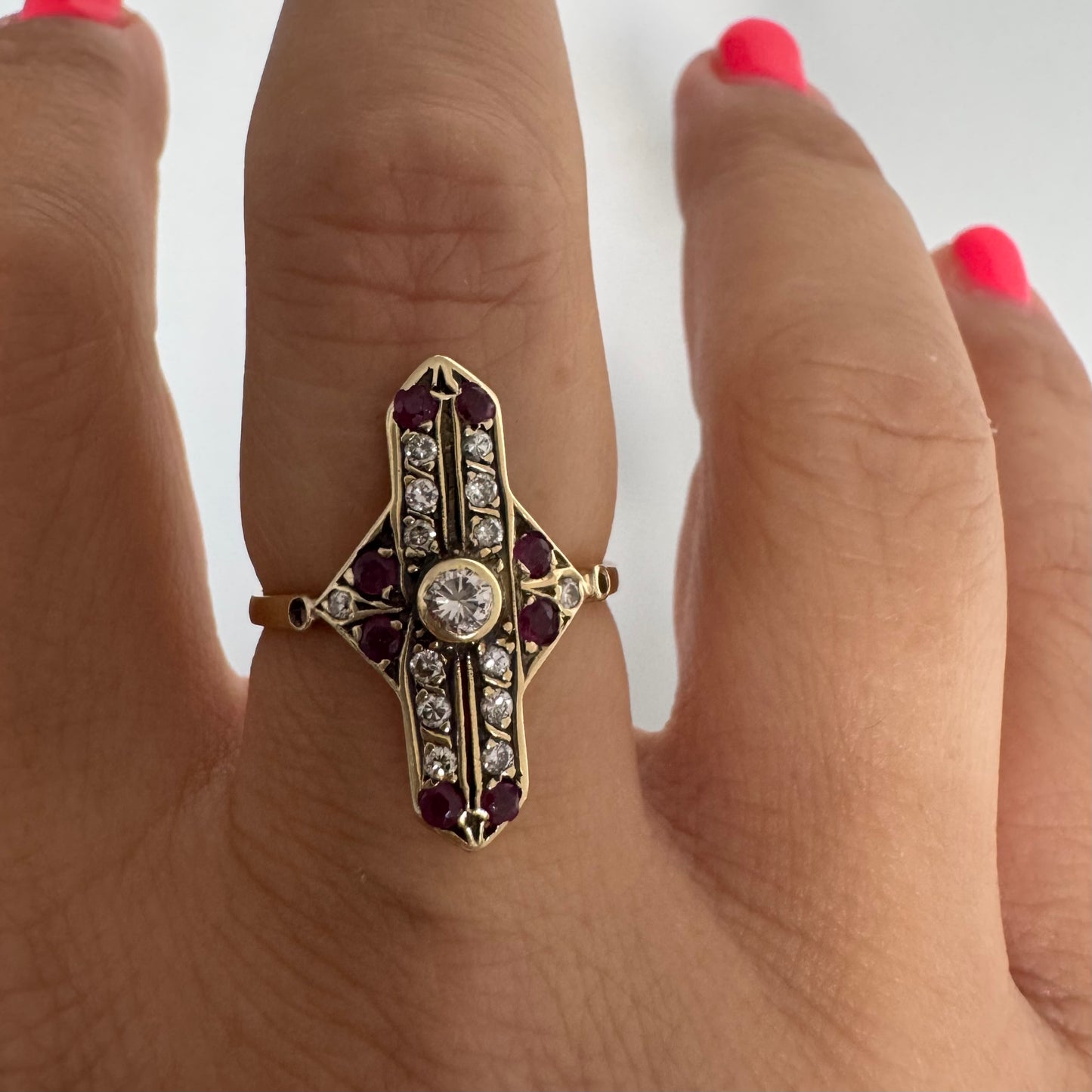 18K gold ring featuring a striking geometric design, set with a central Diamond surrounded by sparkling Diamonds and rich red Rubies.