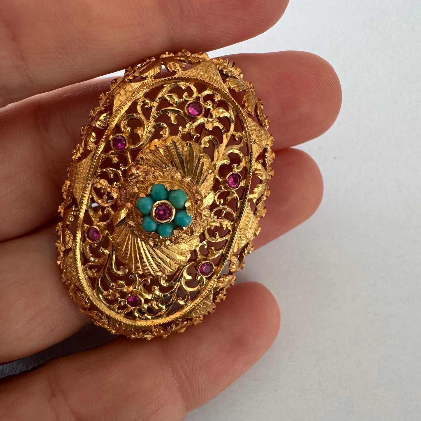 18K gold filigree brooch featuring intricate openwork detailing, accented with Ruby & Turquoise arranged in a floral centerpiece