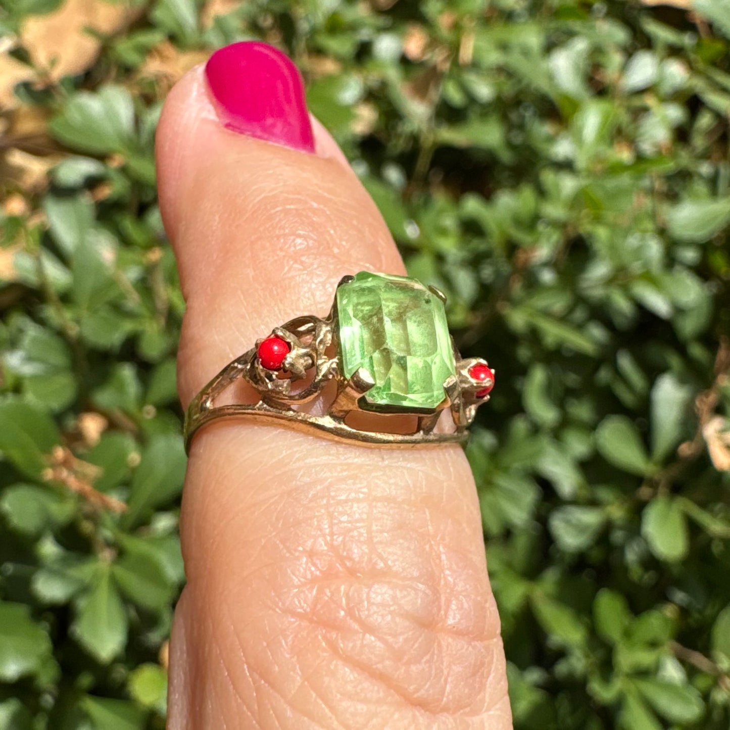 14K gold ring set with a vibrant emerald-cut Peridot at its center, flanked by two delicate red Coral accents