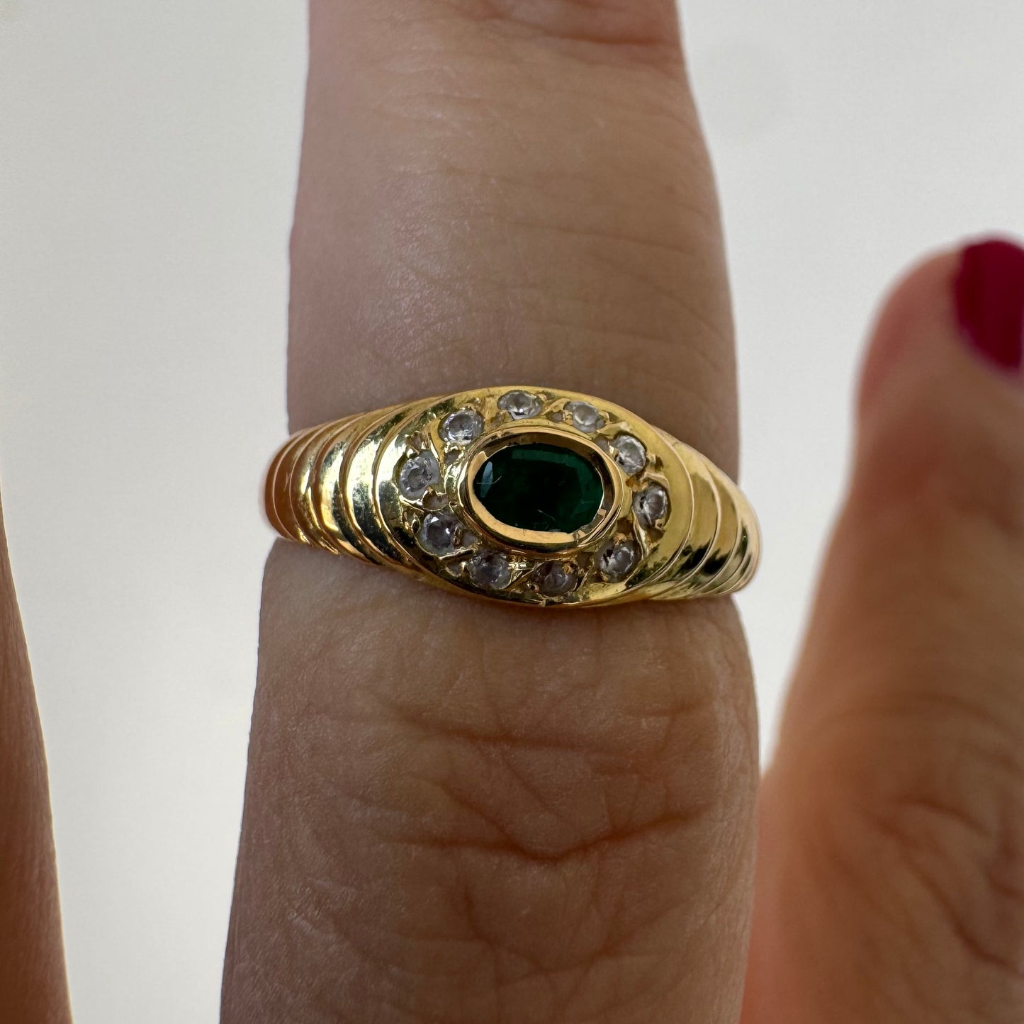 18K gold ring set with an oval Emerald at the center surrounded by Diamonds