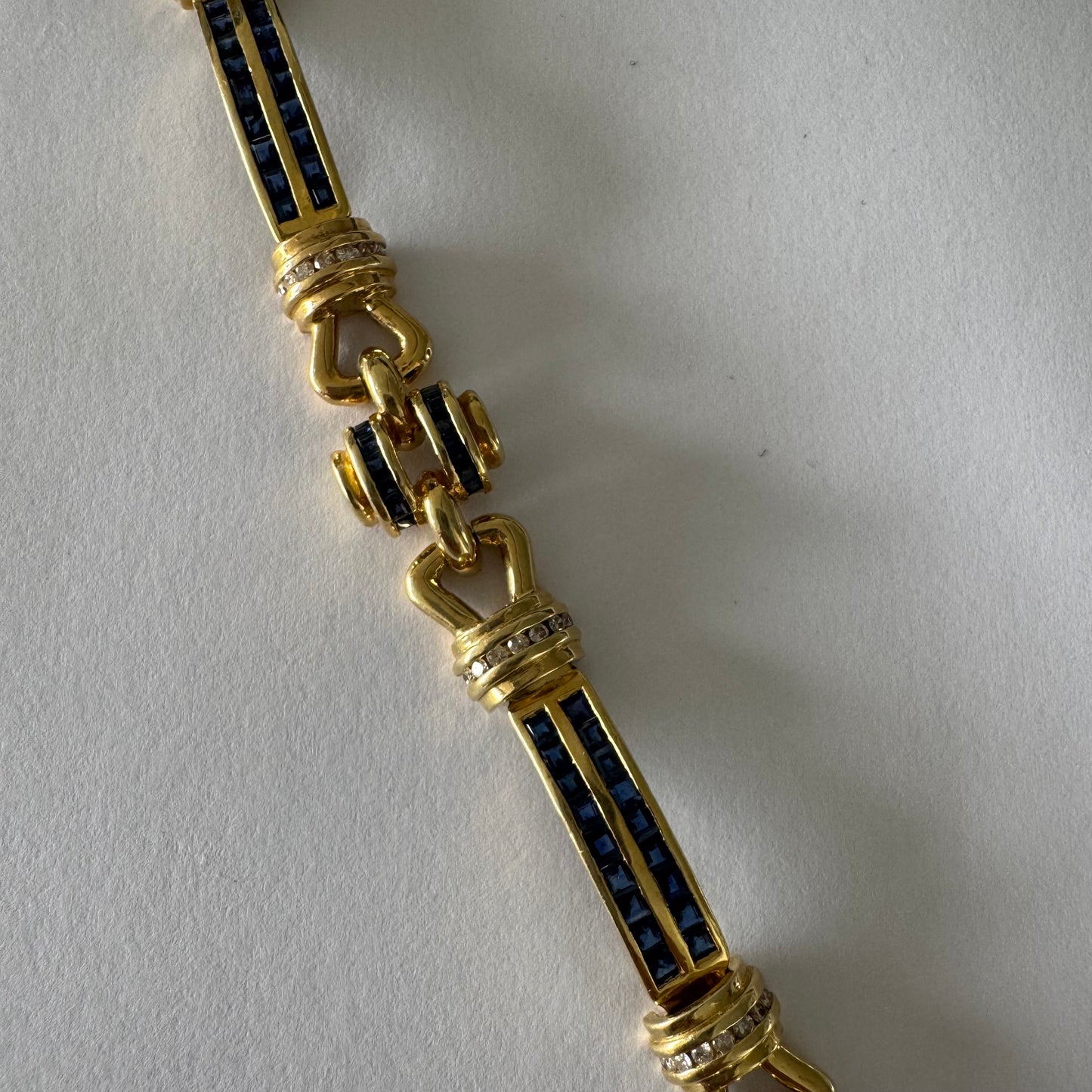 18K gold bracelet featuring a bold link design set with deep blue Sapphires and a subtle Diamond accent at the center.