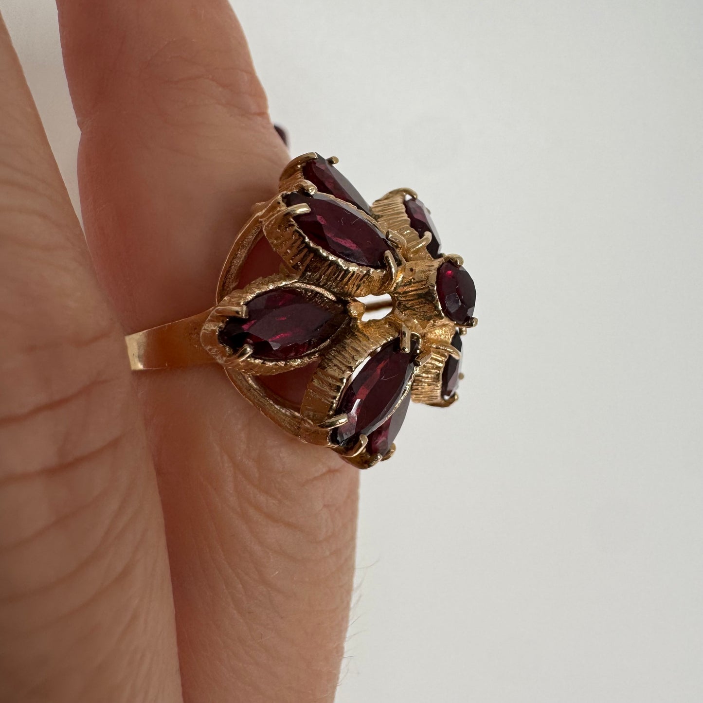 14K gold ring set with marquise-cut Garnets surrounding a round central stone.