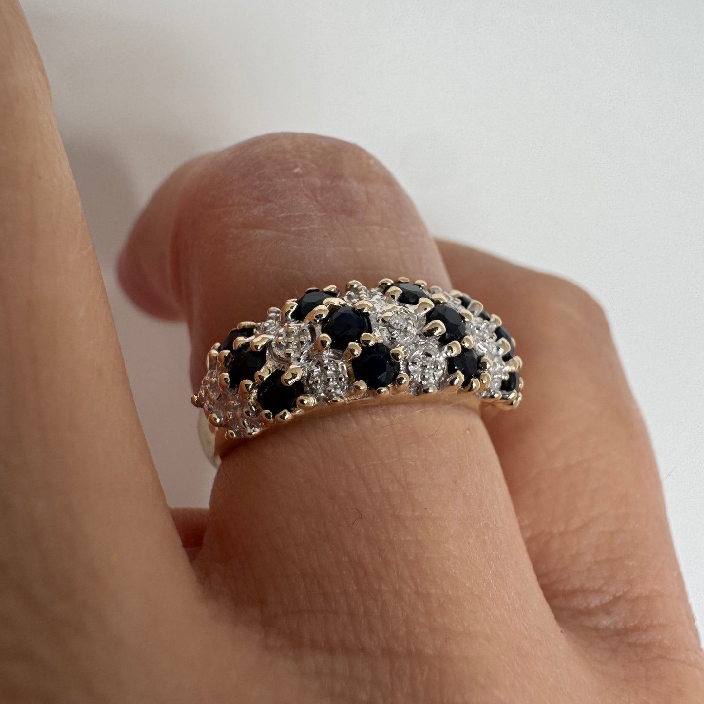 טבעת זהב צהוב 10 קראט משובצת אבני ספיר כהות ויהלומים בעיצוב קלאסי ורומנטי.