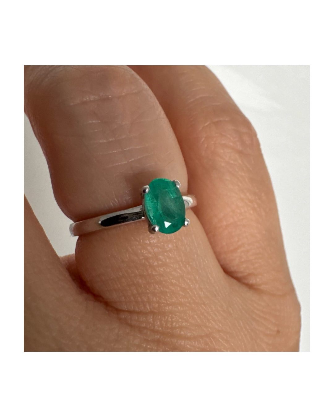 טבעת זהב לבן 14 קראט משובצת אבן אמרלד אובלית בגוון ירוק עשיר.