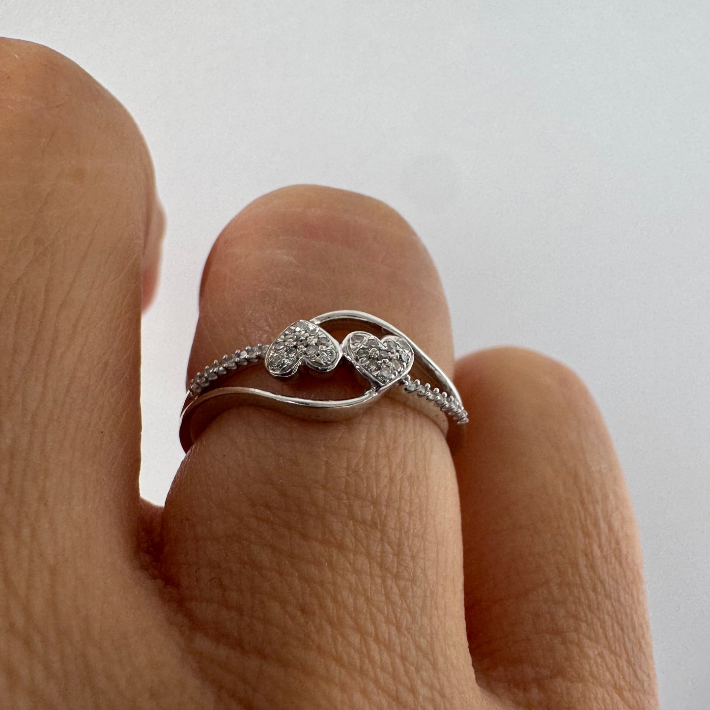 14K gold ring featuring a delicate and romantic design with two connected diamond hearts