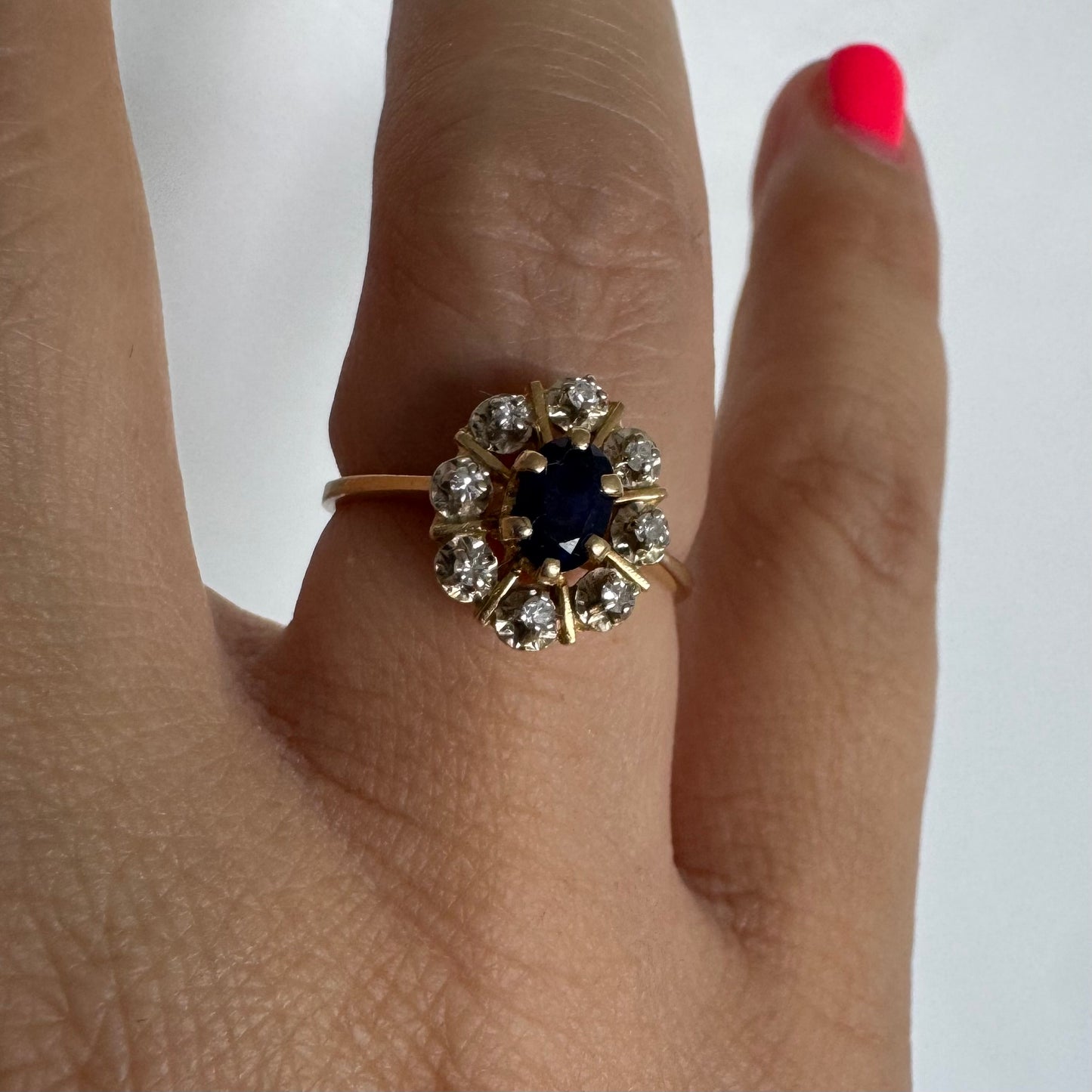 18K gold ring set with a natural blue Sapphire at its center, surrounded by a halo of sparkling Diamonds